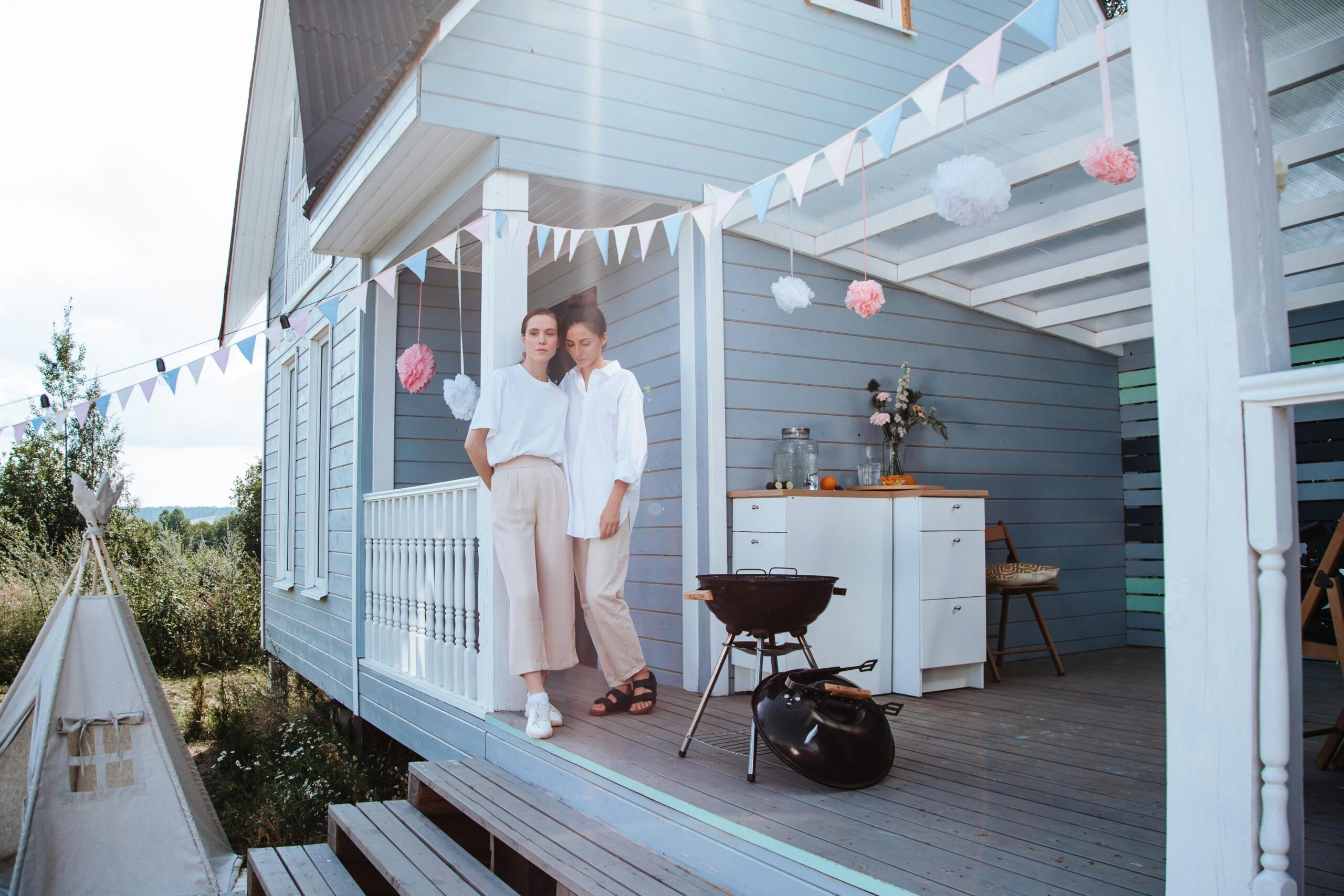 Two women standing together on a decorated porch, enjoying a peaceful summer day.